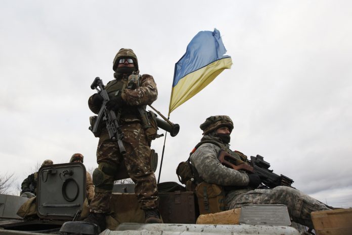 Ukrainian servicemen ride on an armored personnel carrier at a checkpoint near the eastern Ukrainian town of Debaltseve in Donetsk region